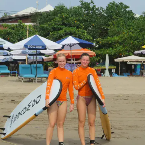 Deux élèves avec leurs planches sur la plage