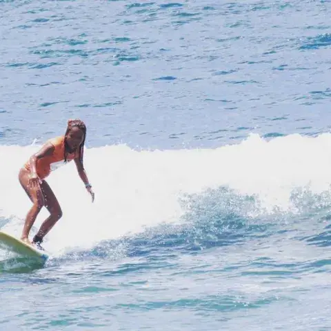 Surfeuse debout sur sa planche dans une vague