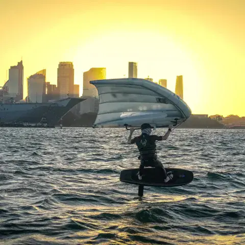 Wing foil au coucher du soleil devant la ligne d'horizon de Sydney