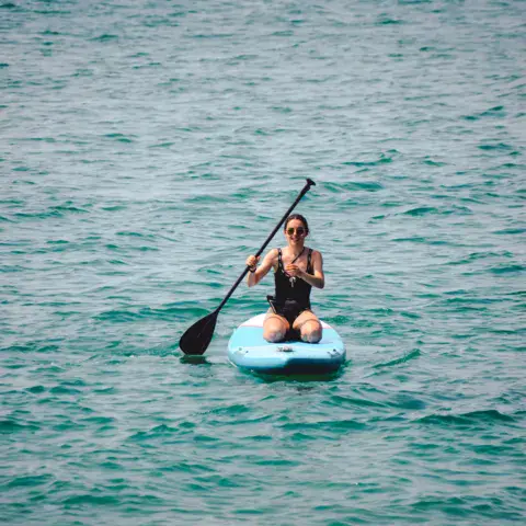 Une pratiquante de stand up paddle sur l'eau