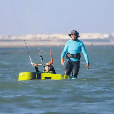 Moniteur de kitesurf accompagnant un élève dans l'eau