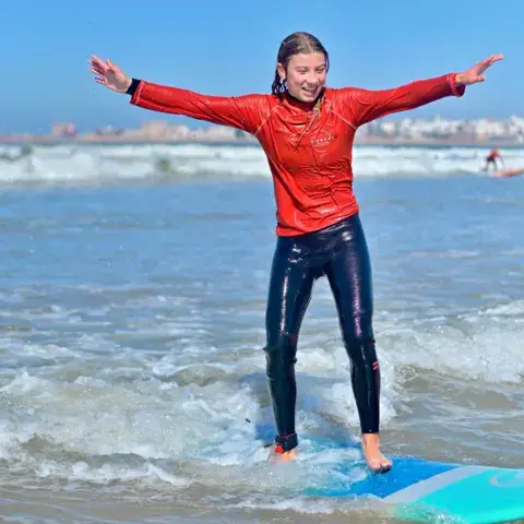 Élève debout sur sa planche dans les vagues de la baie