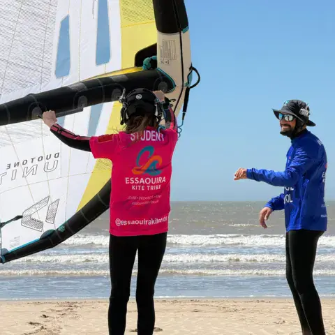 Élève de wingfoil et moniteur sur la plage