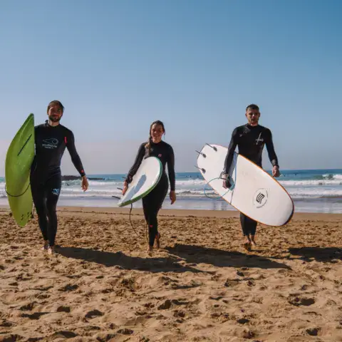 Surfeurs et moniteur de retour de l'eau avec leurs planches
