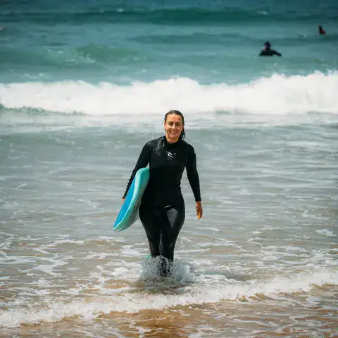 Surfeuse sortant de l'eau avec sa planche