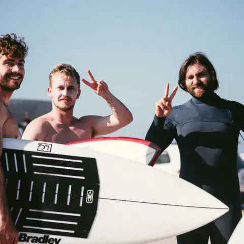 Trois surfeurs avec une planche après la session