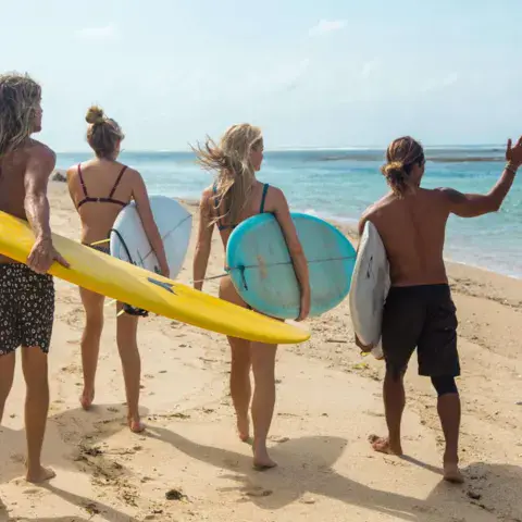 Surfeurs en route vers l'eau avec leurs planches