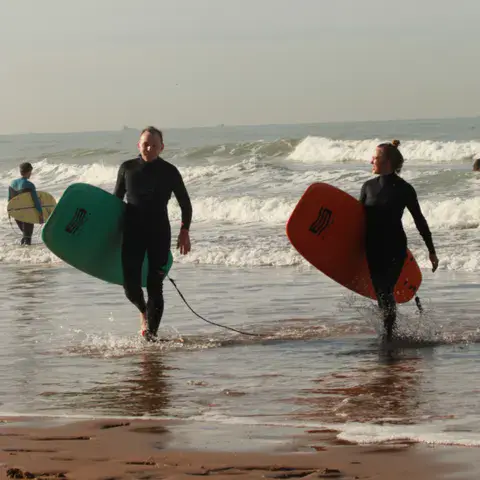 Surfeurs sortant de l'eau avec leurs planches
