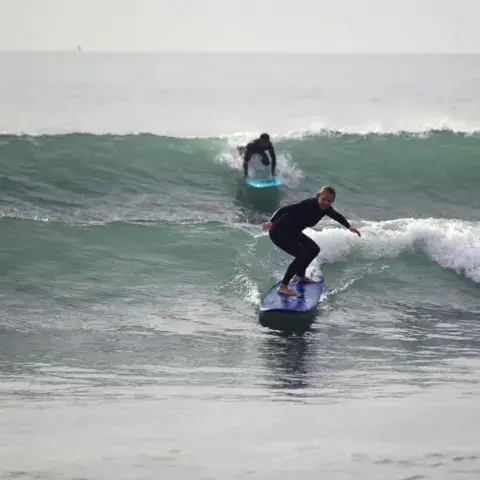 Élèves de surf dans les vagues de la baie