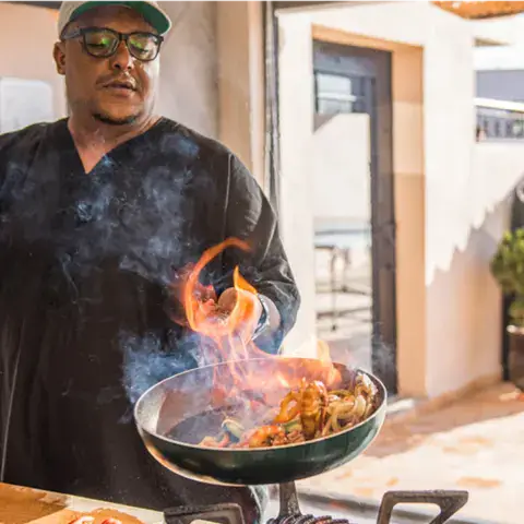 Le chef de la maison préparant un plat flambé