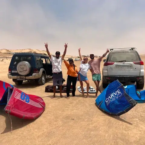 Groupe devant les 4x4 et les ailes étalées dans les dunes