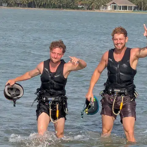 Deux kitesurfeurs sortant de l'eau, harnais et casque