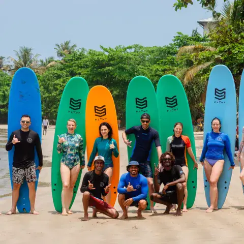 Équipe et élèves alignés devant les planches sur la plage