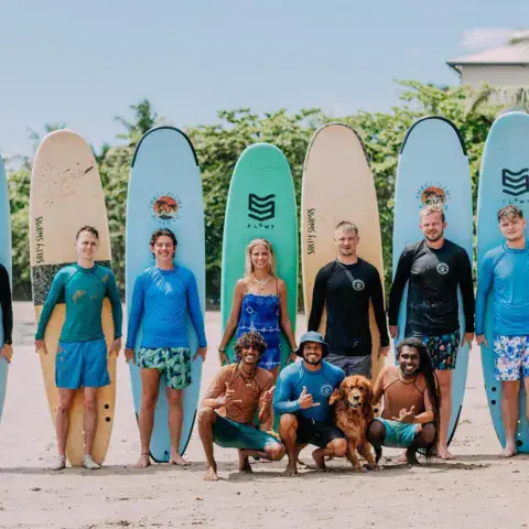 Groupe de surfeurs avec leurs planches et un chien sur la plage