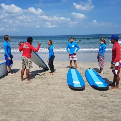 Groupe d'élèves et moniteurs avec leurs planches sur la plage