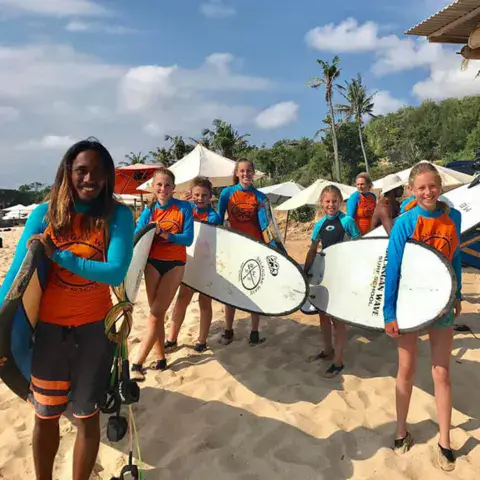 Moniteur et élèves avec leurs planches sur la plage