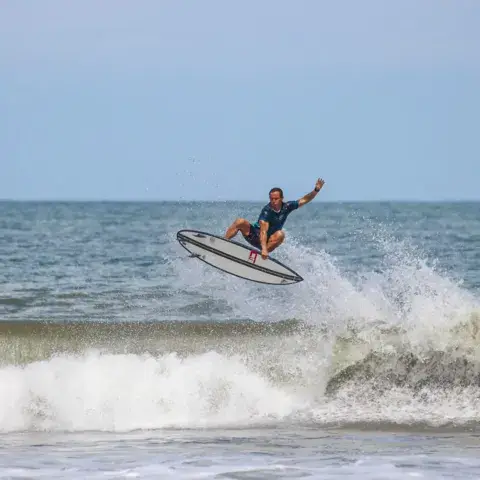 Un surfeur décolle sur une vague