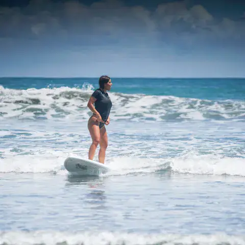 Une élève debout sur sa planche dans les vagues