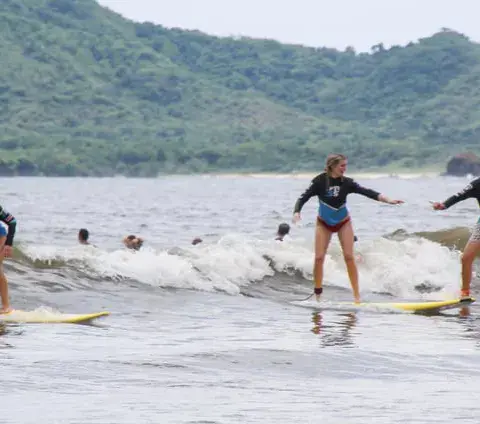 Deux élèves debout sur leur planche dans les vagues