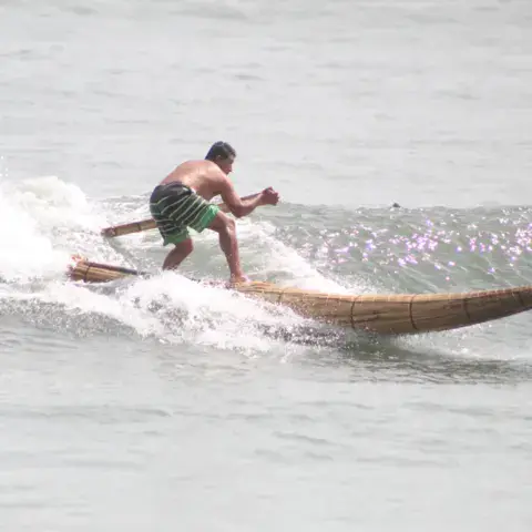 Surfeur debout sur un caballito de totora