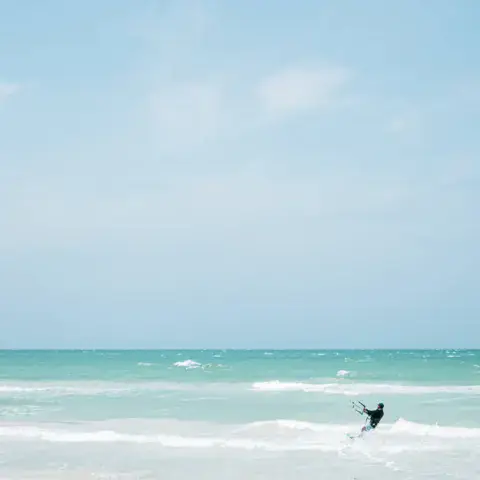 Kitesurfeur sous un kite jaune, mer turquoise