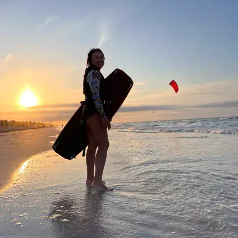 Pratiquante sur la plage avec une planche de kite