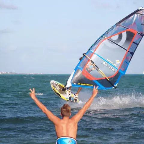 Windsurfeur sur l'eau, bras levés au premier plan