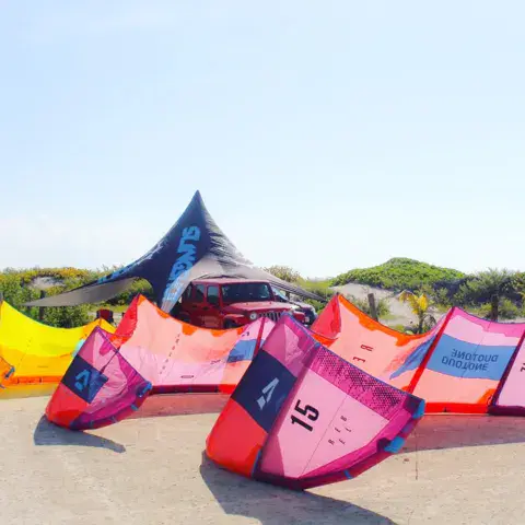 Kites posés sur le sable à côté d'une tente