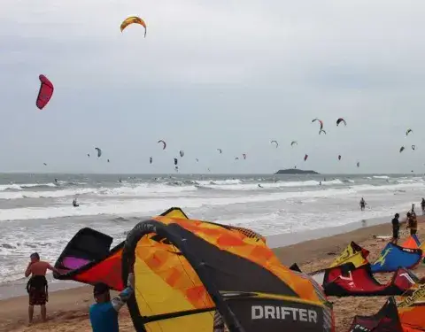 Des ailes étalées sur la plage de Mui Ne, avec des kitesurfeurs sur l'eau