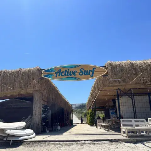 Enseigne du centre et abris de roseau face à la plage