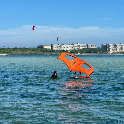 Rider en wing foil, kites au loin