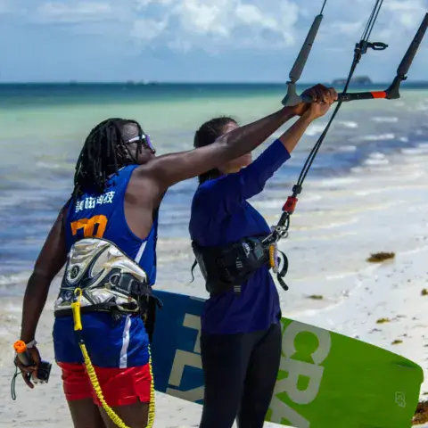 Un moniteur règle la barre avec une élève sur la plage