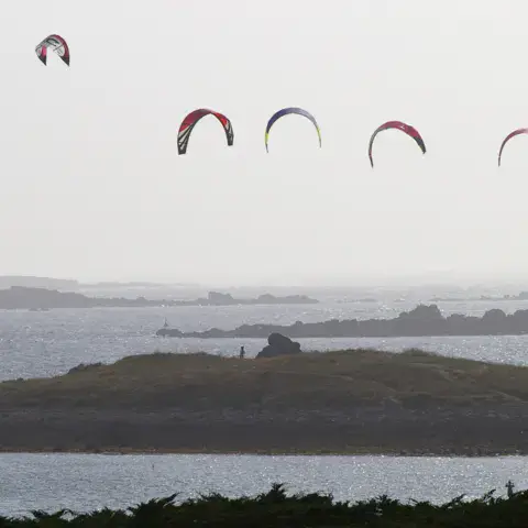 Kitesurfs devant un îlot de la côte