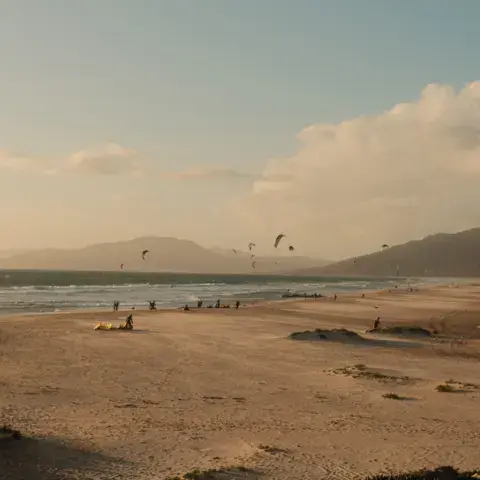 Plage de sable avec des kitesurfeurs en fin de journée