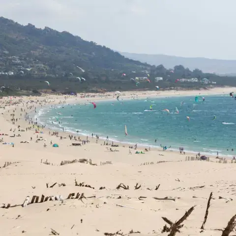 Grande plage de sable avec des kites dans le ciel