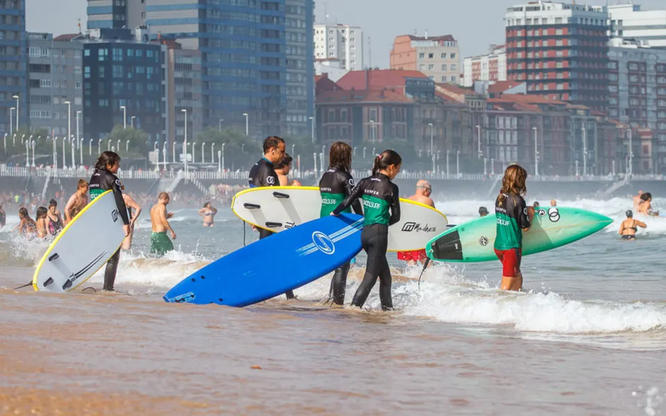 Groupe en combinaison alignées derrière des planches colorées sur la plage, ville en arrière-plan