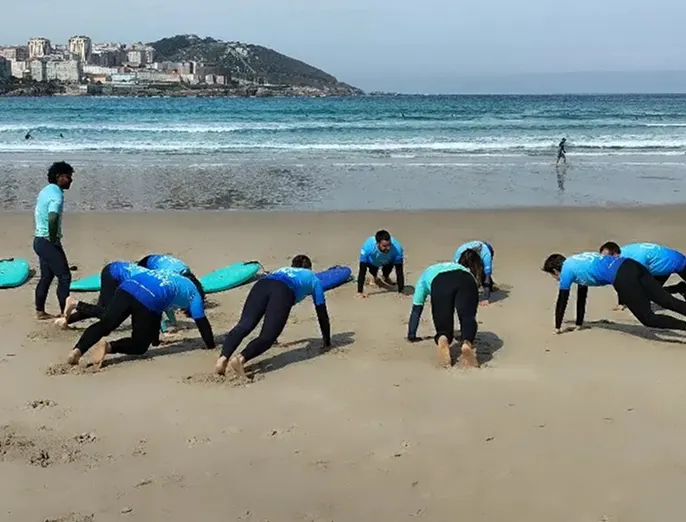 Échauffement d'un groupe en combinaison sur la plage, ville en arrière-plan
