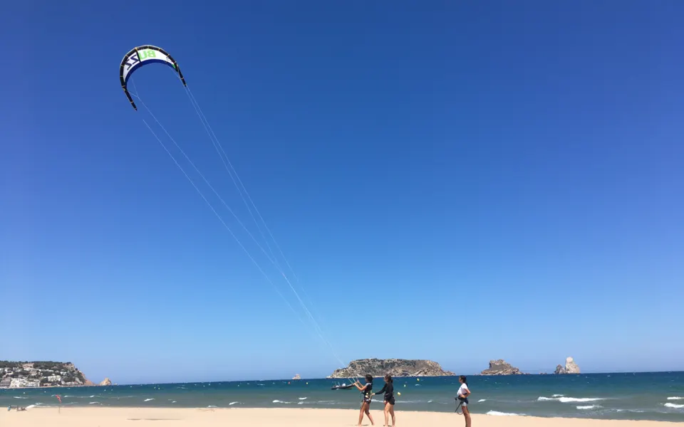 Plage avec un kite dans le ciel et les îles au large