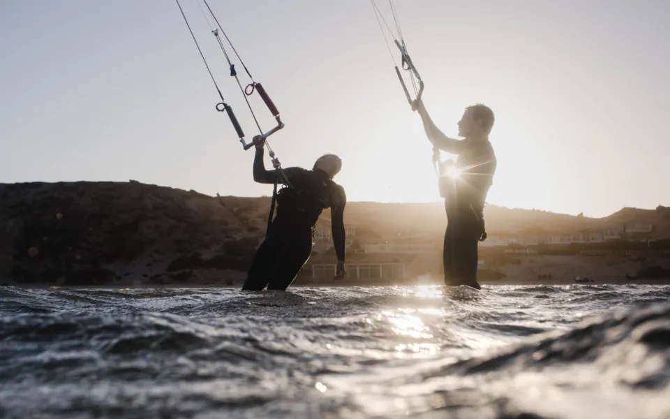 Deux kitesurfeurs à contre-jour, ailes en l'air