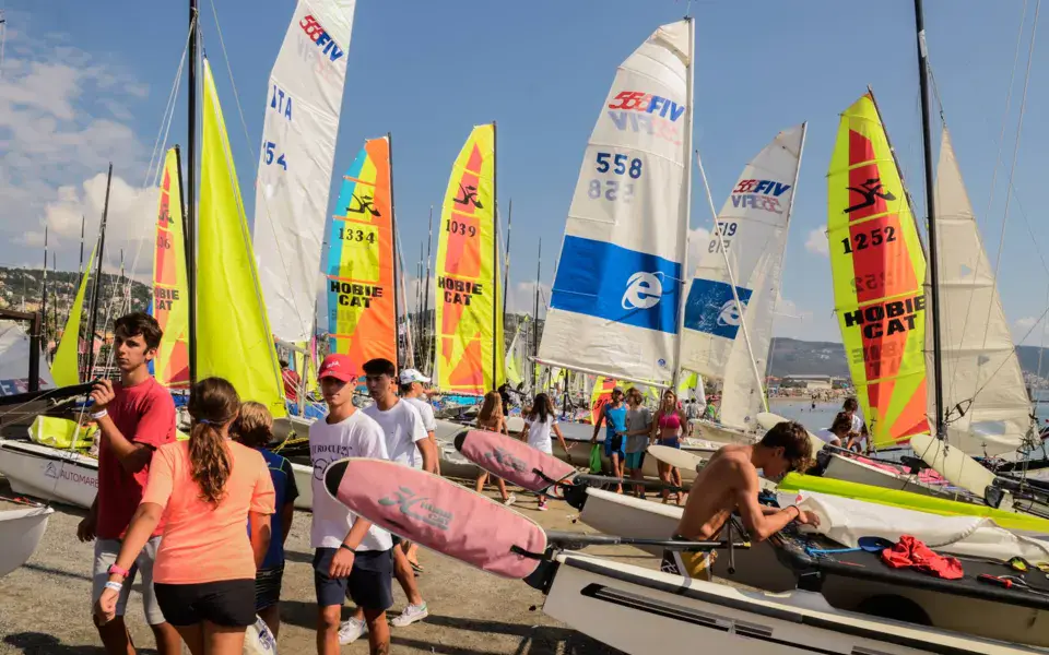 Voiles de dériveurs et de windsurfers sur la plage du club