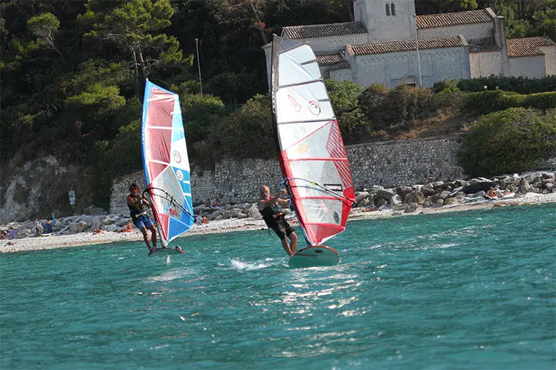 Deux windsurfeurs en navigation au pied de la falaise de Portonovo