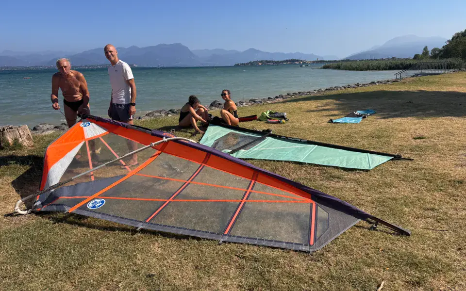 Voiles de windsurf étalées sur l'herbe au bord du lac