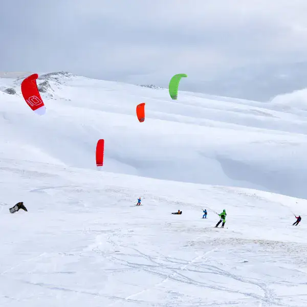 Plusieurs snowkiters sur une pente enneigée