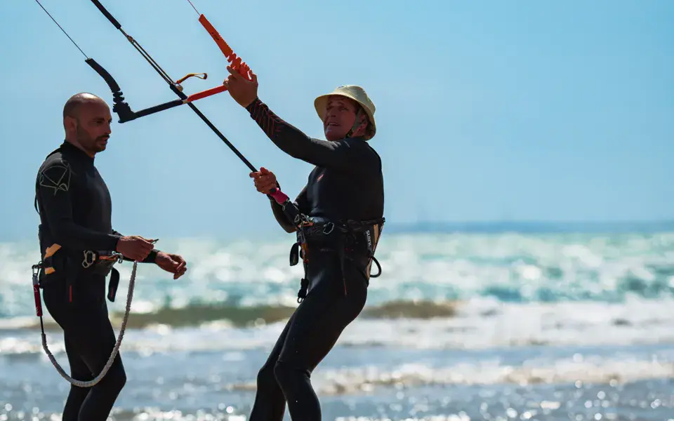 Deux kitesurfeurs préparant leurs ailes au bord de l'eau