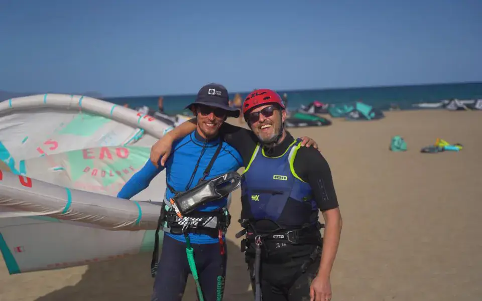 Deux riders devant une aile de kitesurf sur la plage