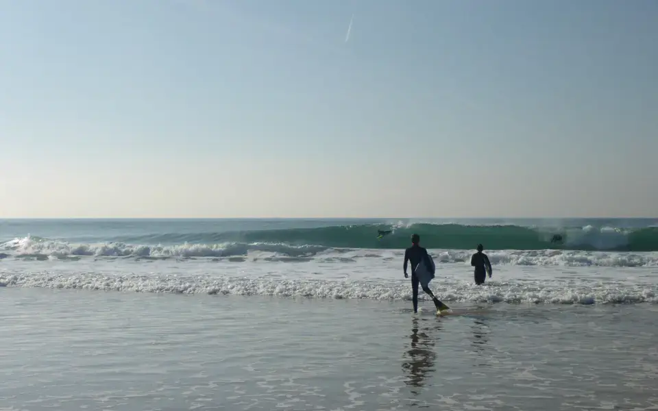 Deux surfeurs entrant dans l'eau avec leurs planches