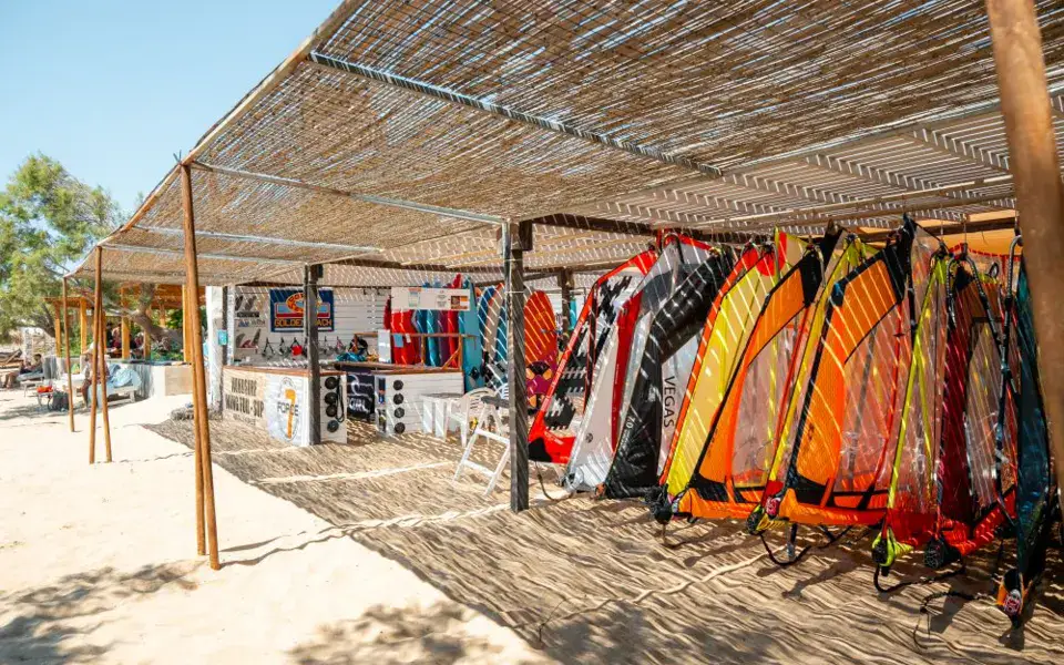 Voiles de windsurf rangées sous un abri en roseaux sur la plage