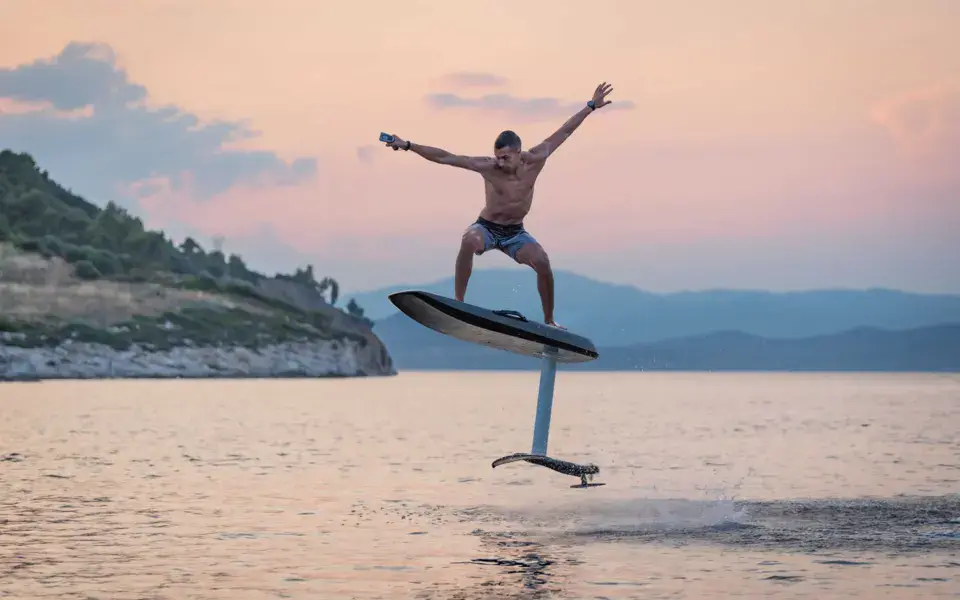 Rider en eFoil au-dessus de l'eau au coucher du soleil