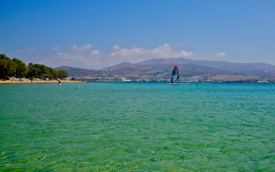 Windsurfeur au loin sur une eau verte peu profonde