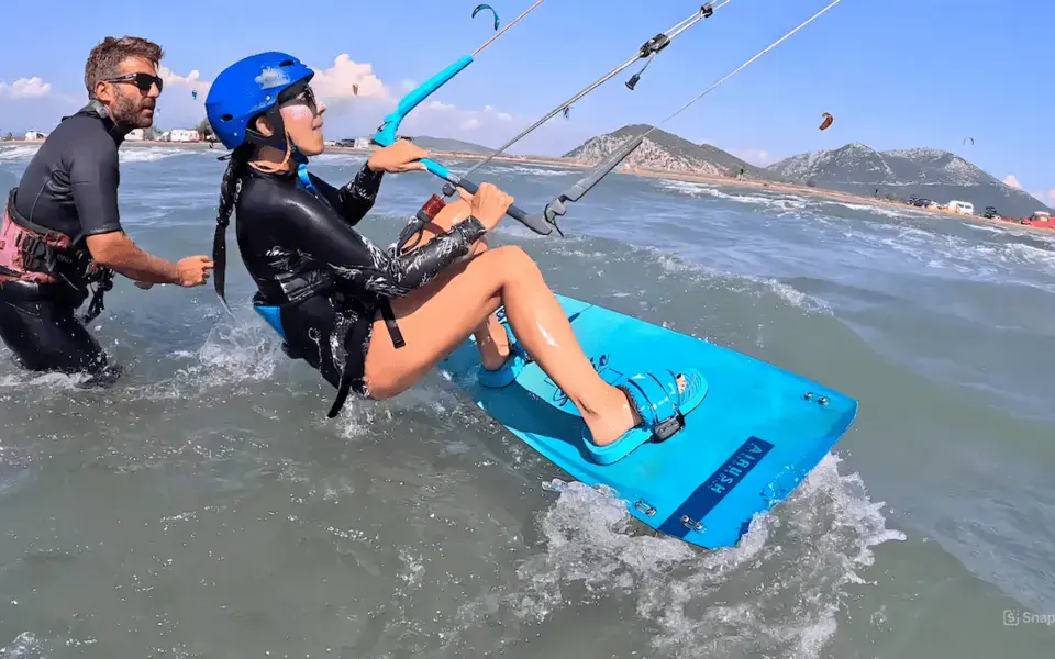 Cours de kitesurf : une élève sur sa planche guidée par l'instructeur